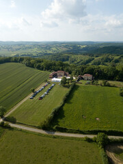 Obraz premium Sarremezan, France. Aerial rural landscape from above, road between green fields and meadows Countryside european village buildings private houses cloudy sky summer