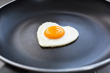 Fried egg in the shape of a heart in a pan