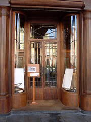 Old wooden entrance to the building with a glass door and storefronts
