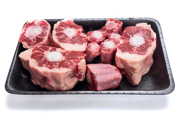 Fresh raw beef ox tail cuts on a plastic trey on white isolated background. Meat industry product.