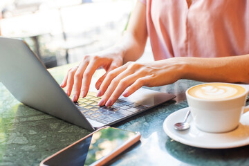 Unrecognizable businesswoman using laptop while working from cafe