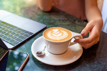View from above of unrecognizable woman sitting at cafe desk and drinking her cappuccino