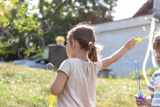 Children blowing bubbles.Outdoor image.Shot of adorable brother and sister blowing bubbles together outside.Cropped shot of two young siblings standing together and blowing bubbles during relaxing day