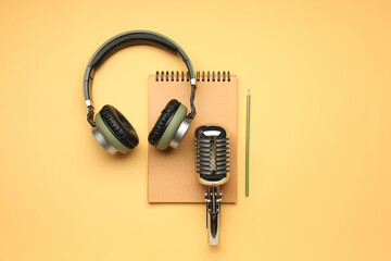 Headphones with microphone and notebook on color background