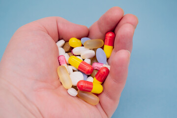 A bunch of colorful pills in my hand on a blue background
