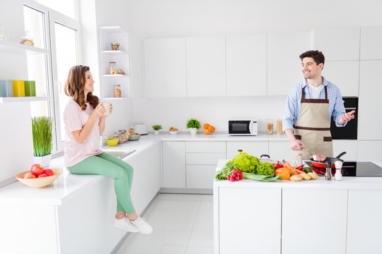 Loving dream harmony family concept. Full length photo of couple enjoy hobby cooking man fry roast meat dinner beef woman sit drink coffee tea cup tell talk say speak in kitchen house indoors