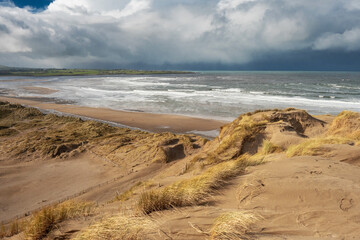 View from a top of a dune on Strandhill beach, county Sligo, Ireland. Atlantic ocean, Blue cloudy sky.