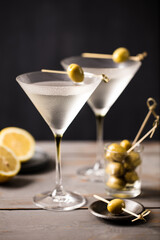 2 glasses of martini with olives. On a wooden background. Portrait