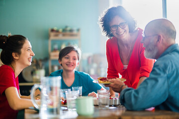 The family gathers around the table in the kitchen to enjoy the delicious strawberry tart that Mom just made.