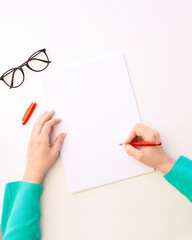 Top view of female hand is writing blank paper on white table
