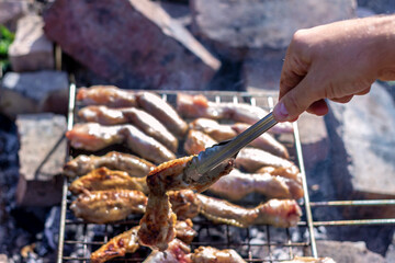 Hands of man preparing barbecue steaks and chicken meat on the grill. People cooking tasty food on barbecue grill outdoors,close-up.Grilling at summer weekend. Fresh meat preparing on grill for lunch.