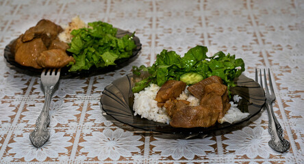 Stir the fried meat in the pan with a wooden spatula.Meat on a plate with green salad and rice.Delicious and healthy food.