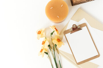 Blank clipboard tablet pad with mock up copy space and narcissus flowers. Flat lay, top view