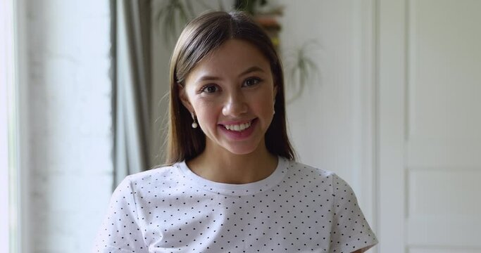 Head shot portrait millennial attractive young woman standing in domestic room smiling looking at camera. Student girl high school admission, satisfied client of beauty or health procedures concept