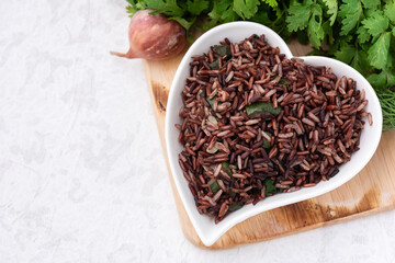 organic red rice in heart plate with vegetable food background