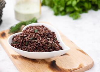 organic red rice in heart plate with vegetable food background