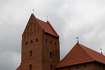 Fototapeta na wymiar Medieval castle in Europe. Red brick castle. Walls and towers of the old castle. Fortress in the middle of the lake Thick stone walls. Tourist place. Medieval architecture and history Trakai Lithuania