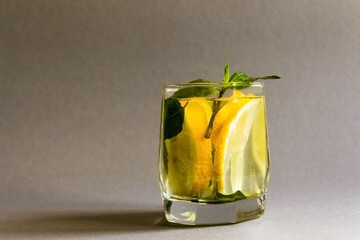 Summer healthy lemonade, cocktails of citrus infused water or mojitos, with lime lemon orange, ice and mint, diet detox beverages, in glasses on gray background.