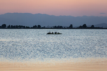 Three people kayaking in a beach lagoon during the sunset