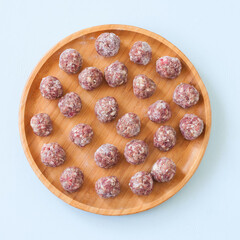 Raw meatballs on a wooden plate. Top view