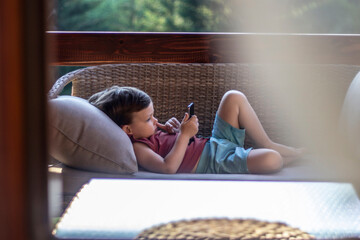 Portrait of small three years old toddler boy addictive on smartphone. Child is using mobile phone....