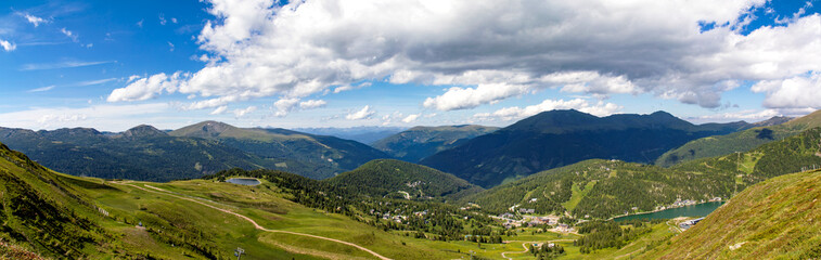 Fototapeta na wymiar Turracher Höhe, Blick ins Tal auf den Turracher See und blauer Himmel, Panorama.