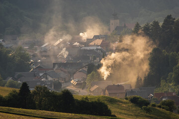 Naklejka na ściany i meble mountain village in the valley suffocating with smoke and smog from wood and coal-fired stoves