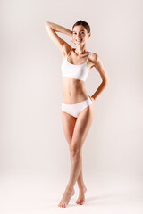 Sporty female in white bra and panties over background.