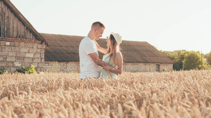 Naklejka na ściany i meble Woman hugging man at sunset in the field