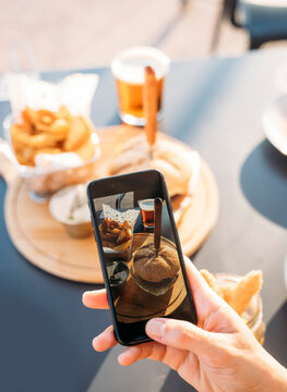 Woman taking a photo with her smartphone to delicious hamburger