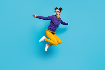 Fototapeta premium Full body profile photo of crazy lady two buns jump high celebrate vacation holidays weekend rejoicing spread arms wear specs shirt pullover pants isolated blue color background