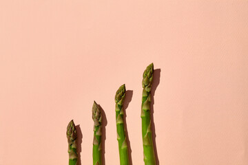 Ripe green asparagus stalks on pink background. Healthy nutrition, food and seasonal vegetables harvest. Close up, flat lay, top view