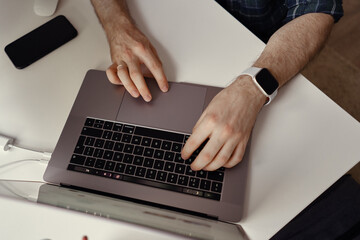 Fototapeta na wymiar Man hands working on his laptop at home. Home office, smart watch on wrist, fingers on keyboard
