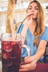 young woman drinking cocktail using the straw