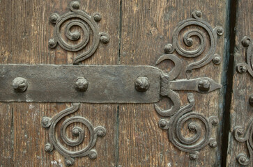 Large grungy wooden gate with metal forged design elements. Weathered wood, historical place in Spain, Europe