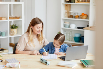 Portrait of smiling adult woman helping girl doing homework or studying at home in cozy interior, copy space