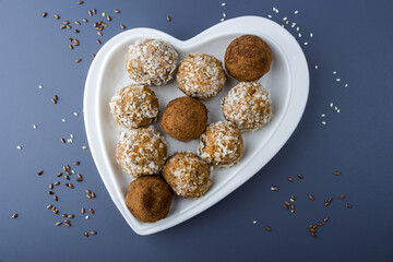 Step by step recipe. Cooking vegetarian energy balls. Step 2 Cooked carrot sweets with nuts, coconut flakes and raisins in heart shaped plate. Raw food desserts. Healthy vegetarian snack.