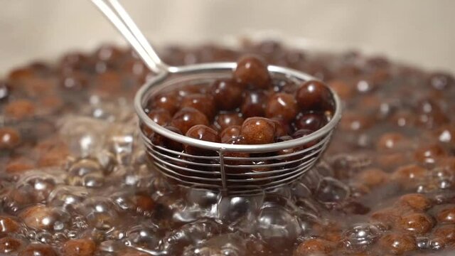 Cooking, boiling brown sugar flavor tapioca pearl balls, ingredient of bubble tea, preparing food and drink, close up, recipe cookbook steps design concept, slow motion.