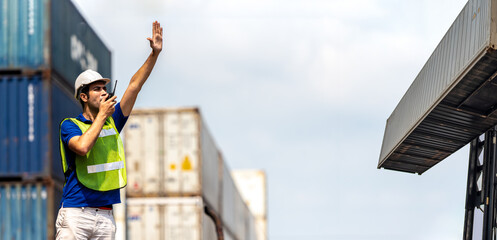 Foreman worker control loading container box to truck on logistic warehouse.