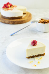 A slice of raw almond cake with raspberries on a white plate. Vegan dessert, healthy food.
