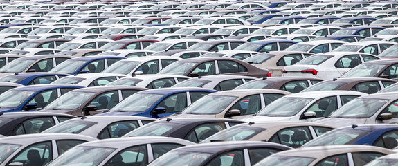Rows of a new cars parked in a distribution center on a car factory on a cloudy day. Top view to...