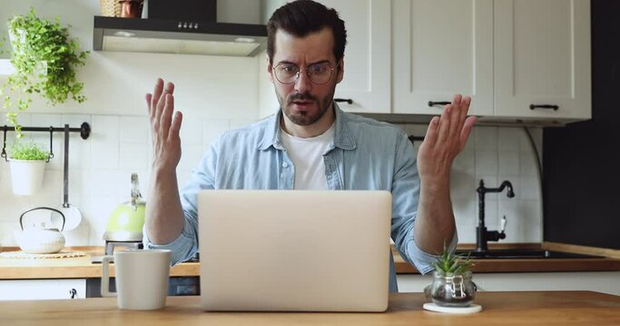Man sit at table in kitchen feels annoyed having problems with laptop. System error, bad e-mail, negative news, data loss, backup battery issues, password wrong, unsaved, lost info need repair concept