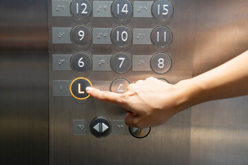 The hand presses on the lobby floor elevator button in hotel