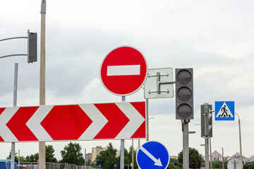 Red and white Do not enter and other signs on gray dull overcast sky background.