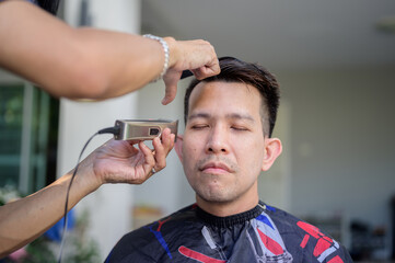 Asian businessman making haircut and salon at home. Outdoor barbershop in garden. Social distancing...