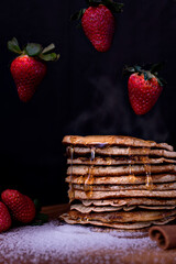 stack of homemade pancakes topped with honey and molasses with strawberries