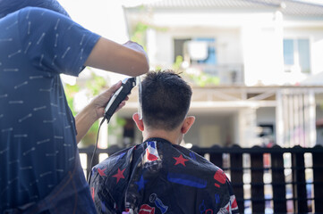 Asian businessman making haircut and salon at home. Outdoor barbershop in garden. Social distancing...
