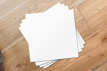 Blank Square Flyers lying on shiny wooden desk
