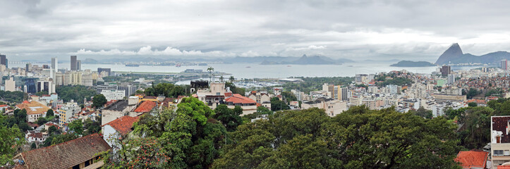 Fototapeta na wymiar Rio de Janeiro, Brazil: panoramic view East from the Ruins Park in Santa Teresa, with sugarloaf mountain to the right and Santos Dumont airport and Niteroi bridge left.