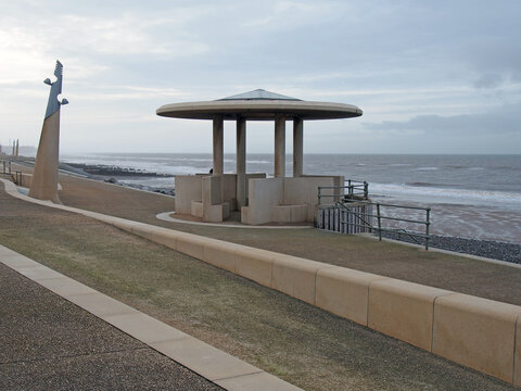 The curved promenade along the seafront at cleveleys in blackpool with steps leading to the sea with the town in the distance